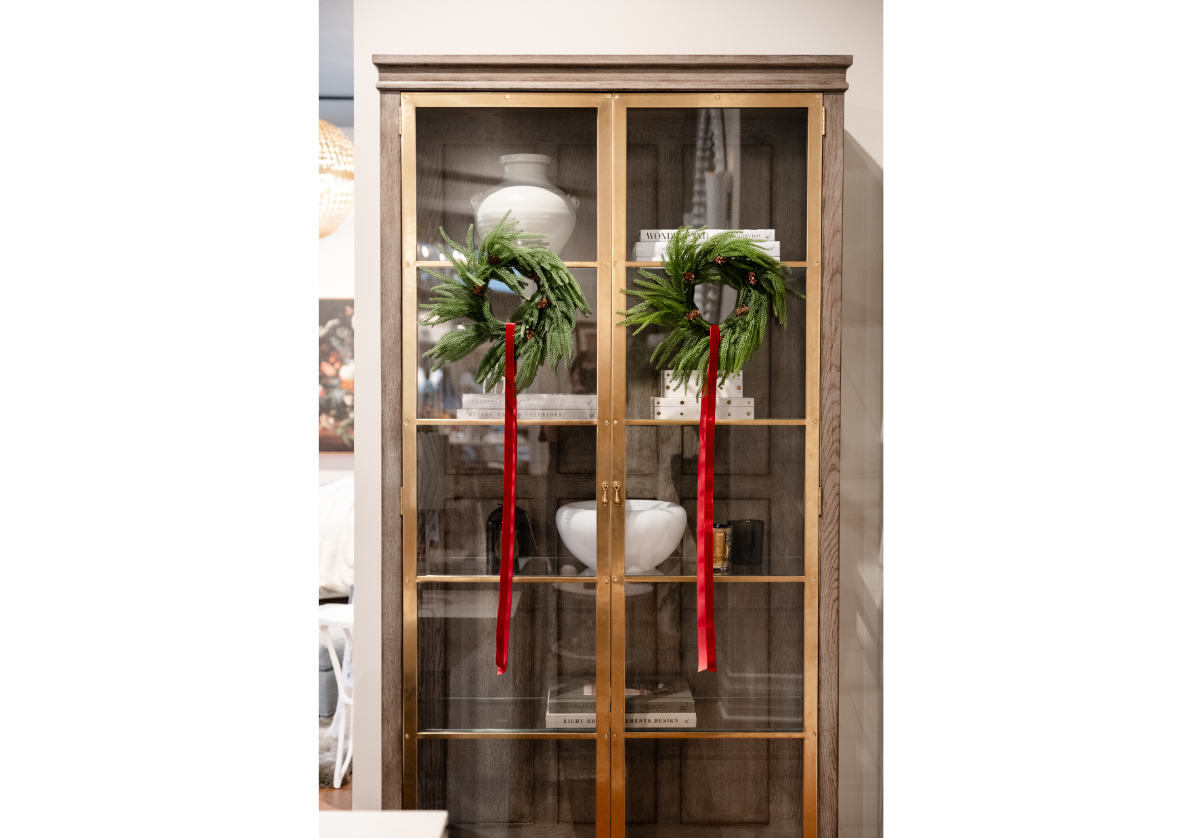 double fir wreaths hung on cabinet doors with pottery and vases inside. 