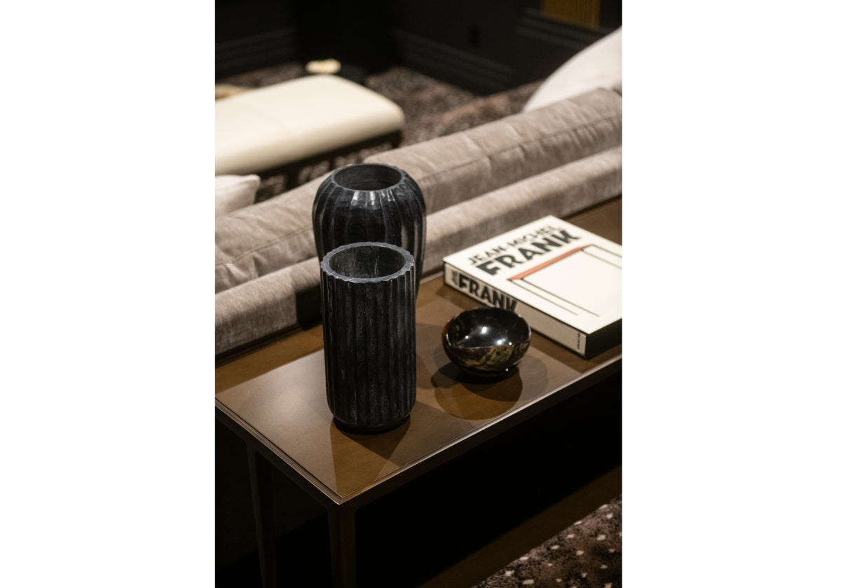 a lifestyle photo of the fauna marble vase sitting on a console table with a book next to it. 