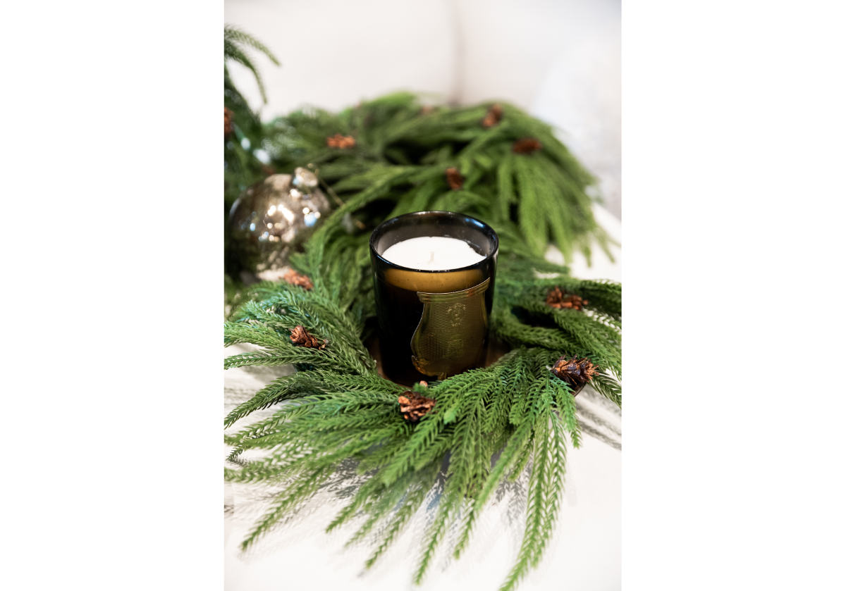 fir wreath with a candle in the center of it. 