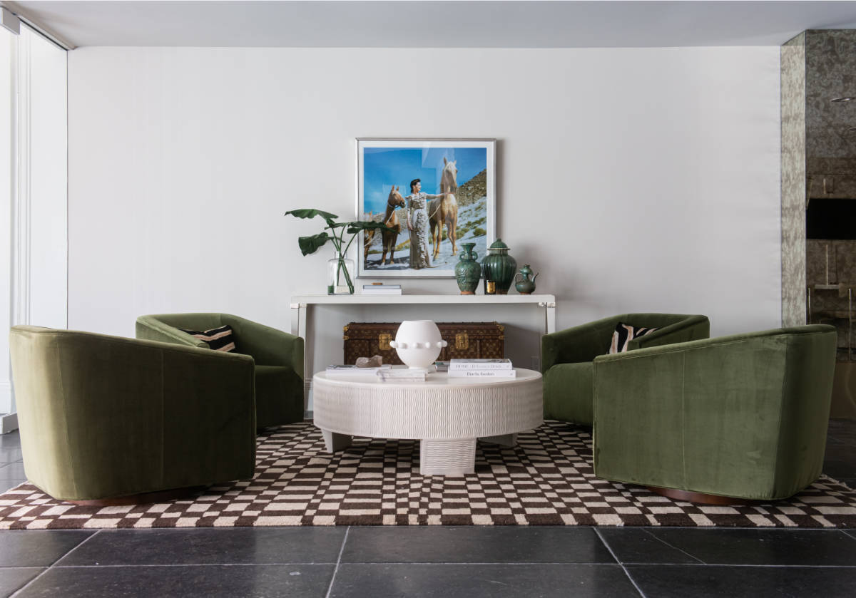 4 green harvey chairs can be seen around a lucca coffee table on top of a chess rug with brown and white checkered design. 