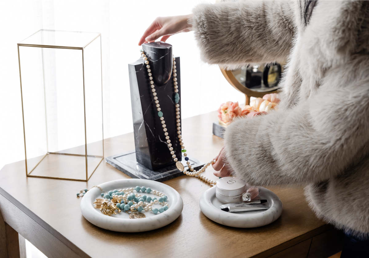 a model is placing a necklace around the darlene necklace display. 