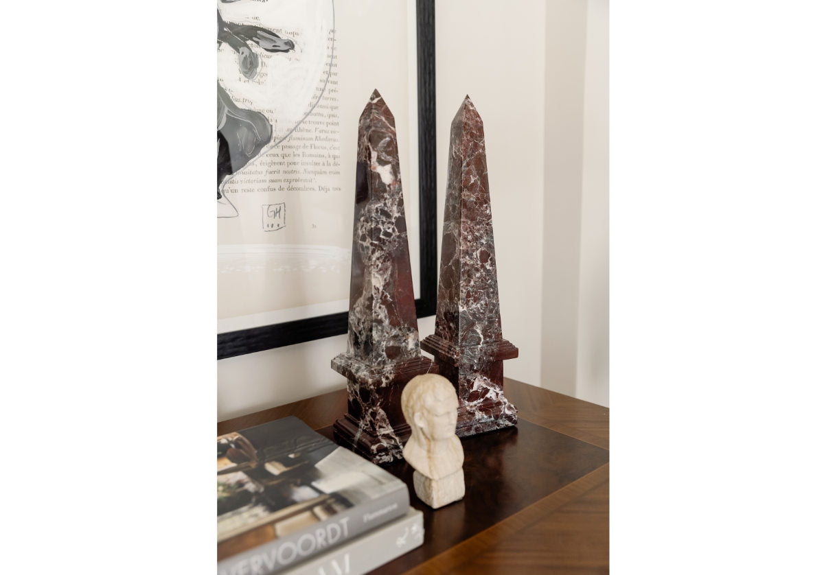 lifestyle picture of marble obelisk on a dresser with books and a decorative statue. 