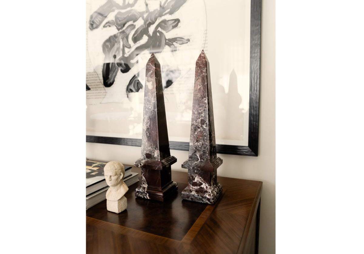 rosso levanto marble, in oxblood color obelisk shown on a dresser next to a decorative statue.