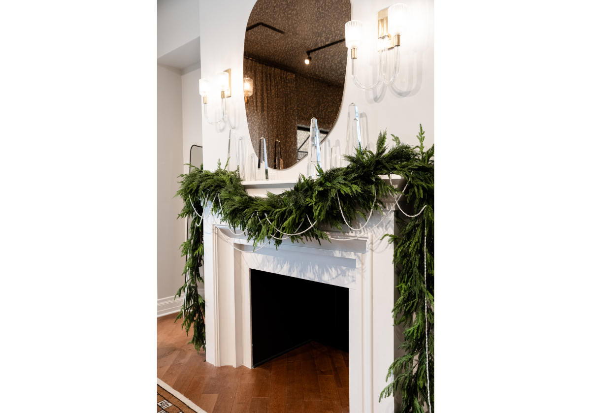 over a large fireplace mantle is a pine and pearl garland with 5 different sized crystal obelisks. 