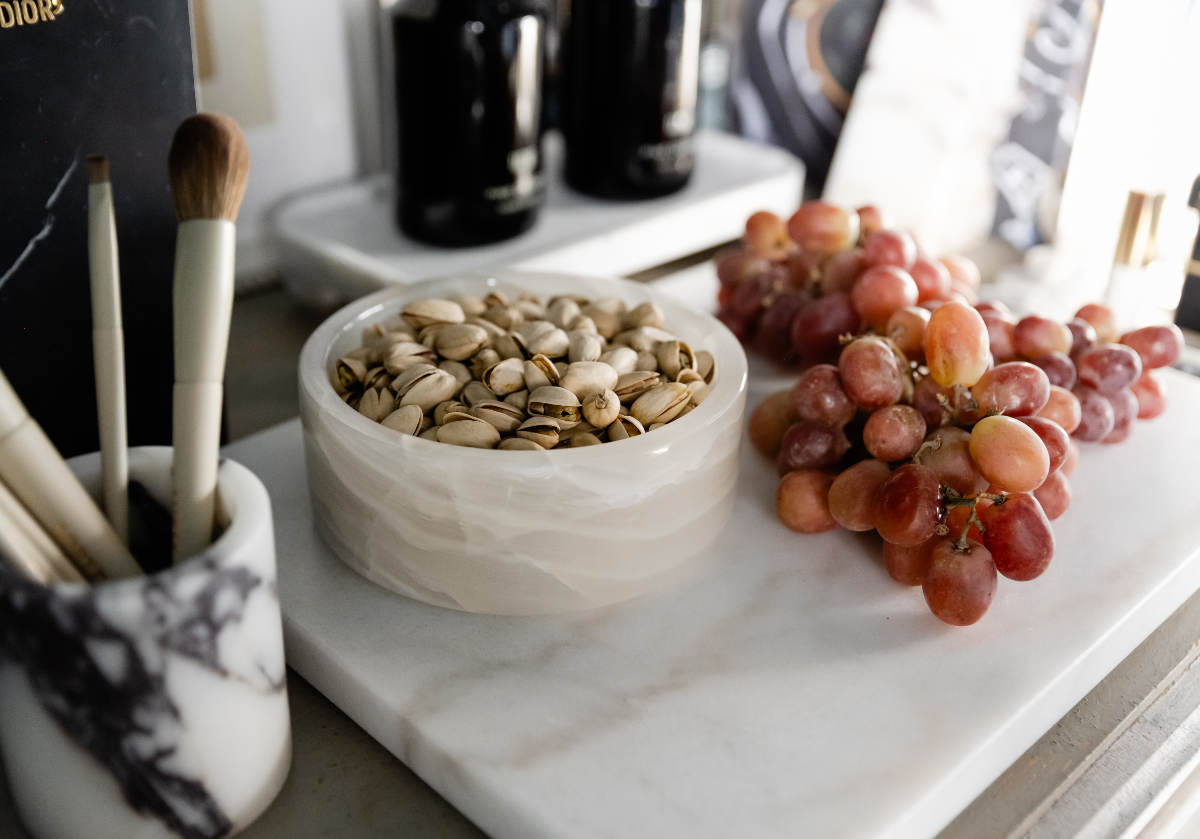 lifestyle photo of marble bowl placed on large white marble tray with grapes. 