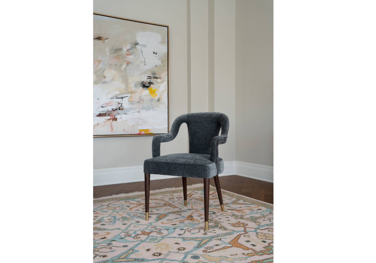 lifestyle photo of the bobbie chair sitting on a rug with a large painting behind it. 