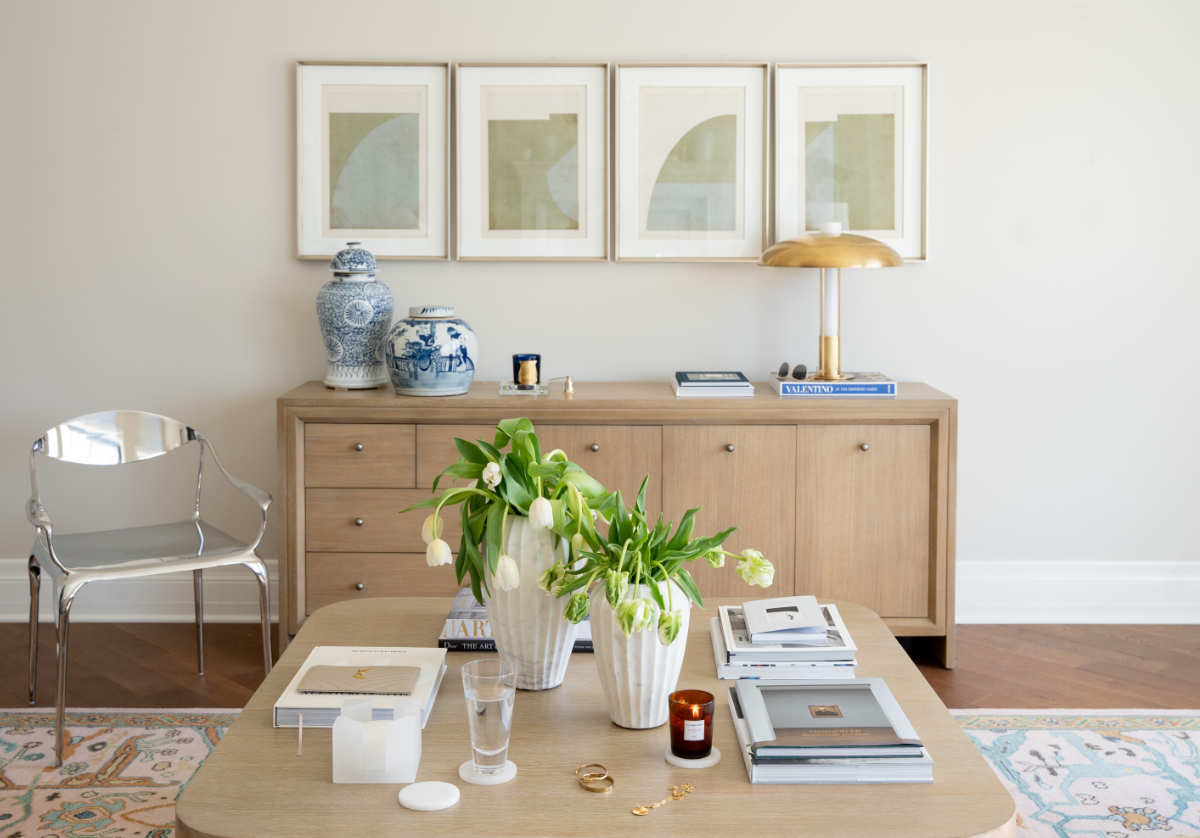 a photo of the blair cocktail table at the bottom of the photo. and the dean dresser in the background. adorned with jars and a lamp. the blair cocktail table has lilies and books on it. 