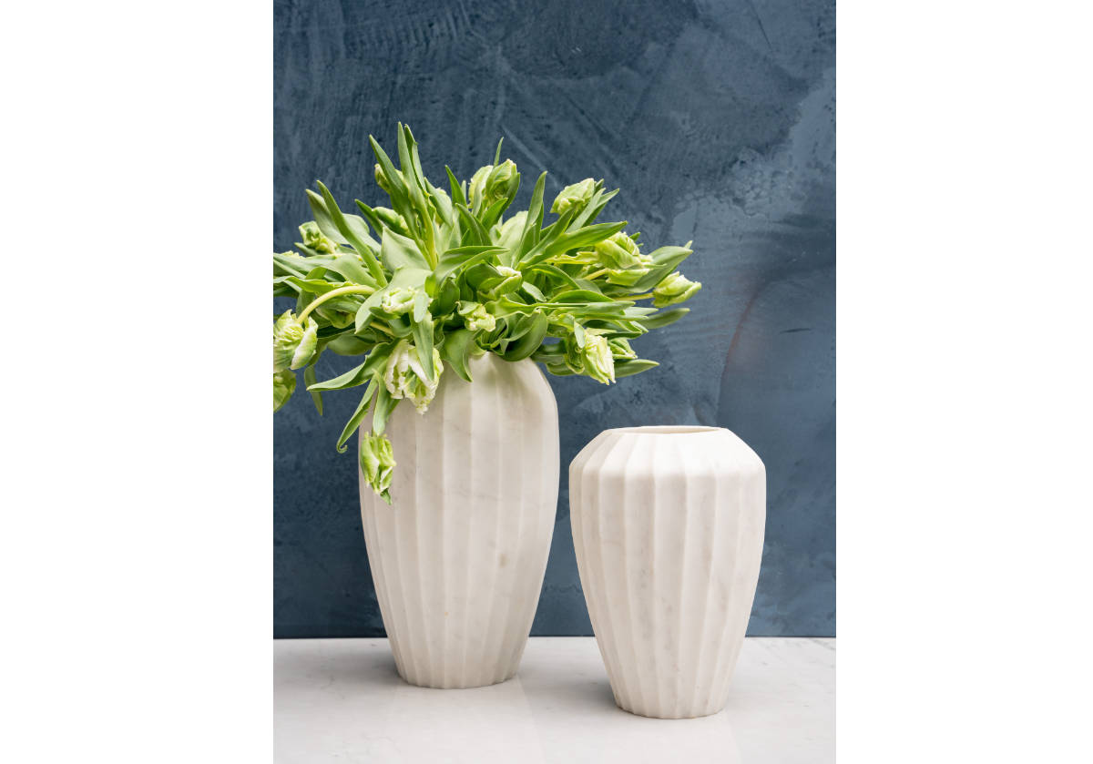 two different sized flora vases can be seen next to each other. ne has flowers inside of it. 