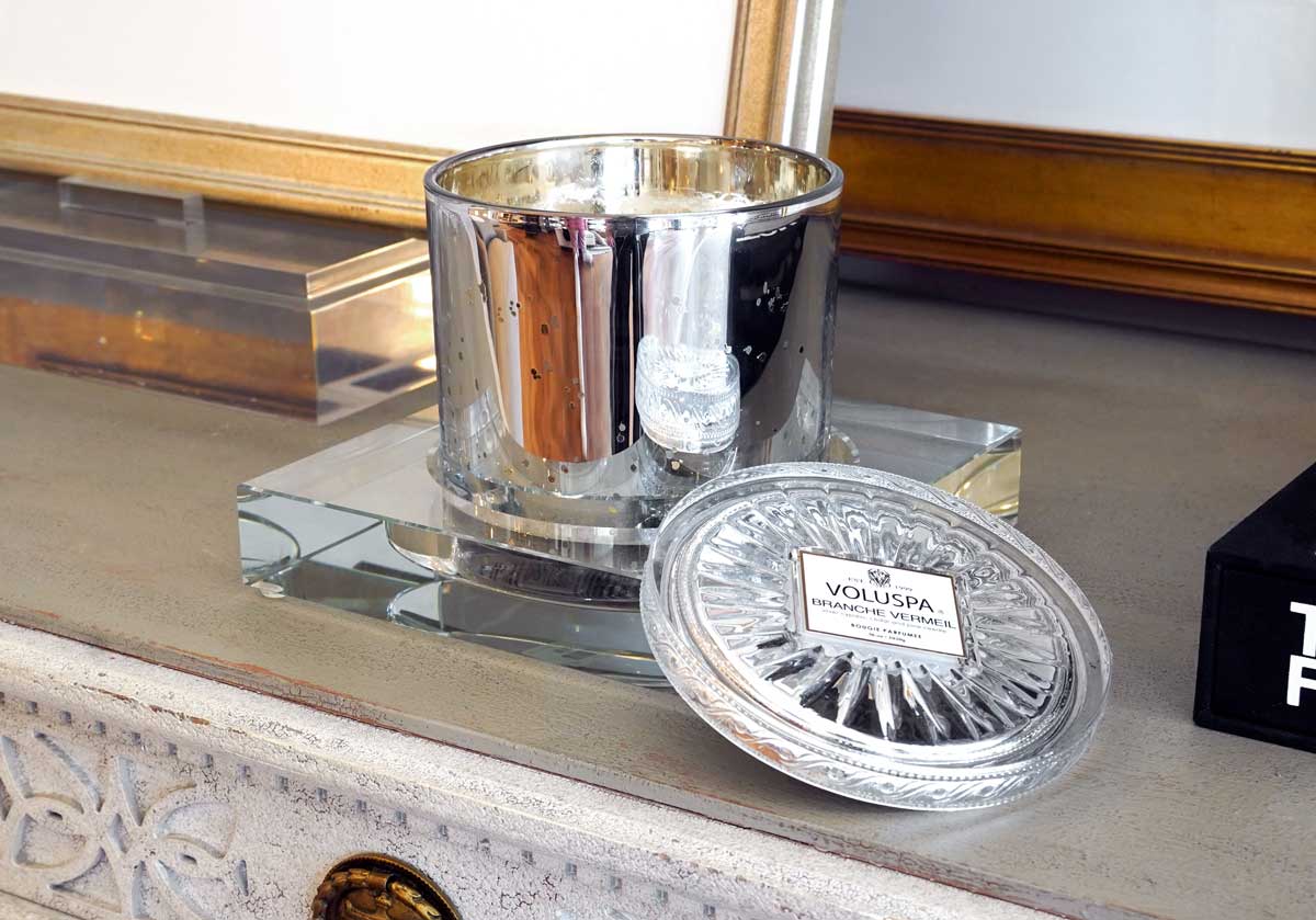 A close up of the crystal candle dish with a large candle inside of it on a dresser. 