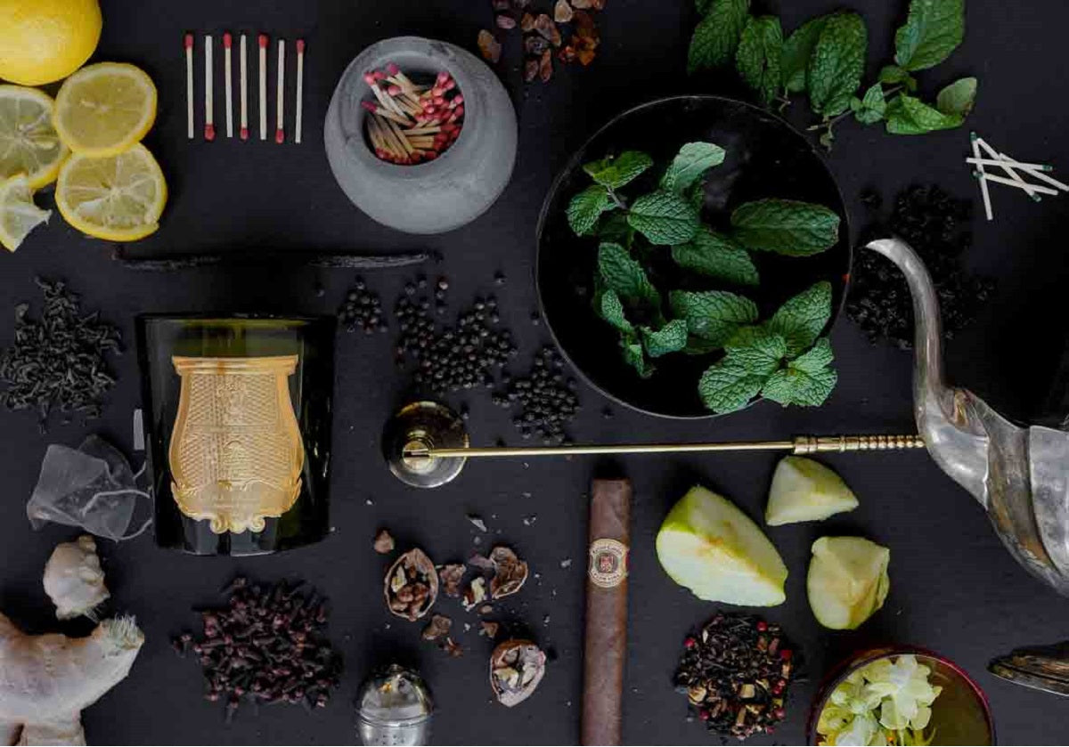 lifestyle photo of the brass candle snuffer surrounded by herbs and mint leaves. 