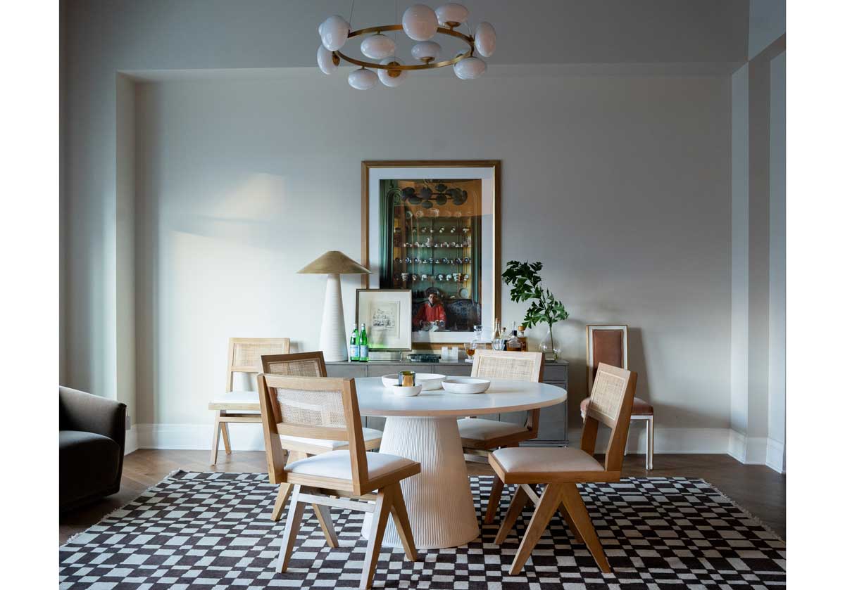 in a living room setting, there is a large chess rug with brown and white checkered design. underneath the lucca dinning table with dining chairs. 