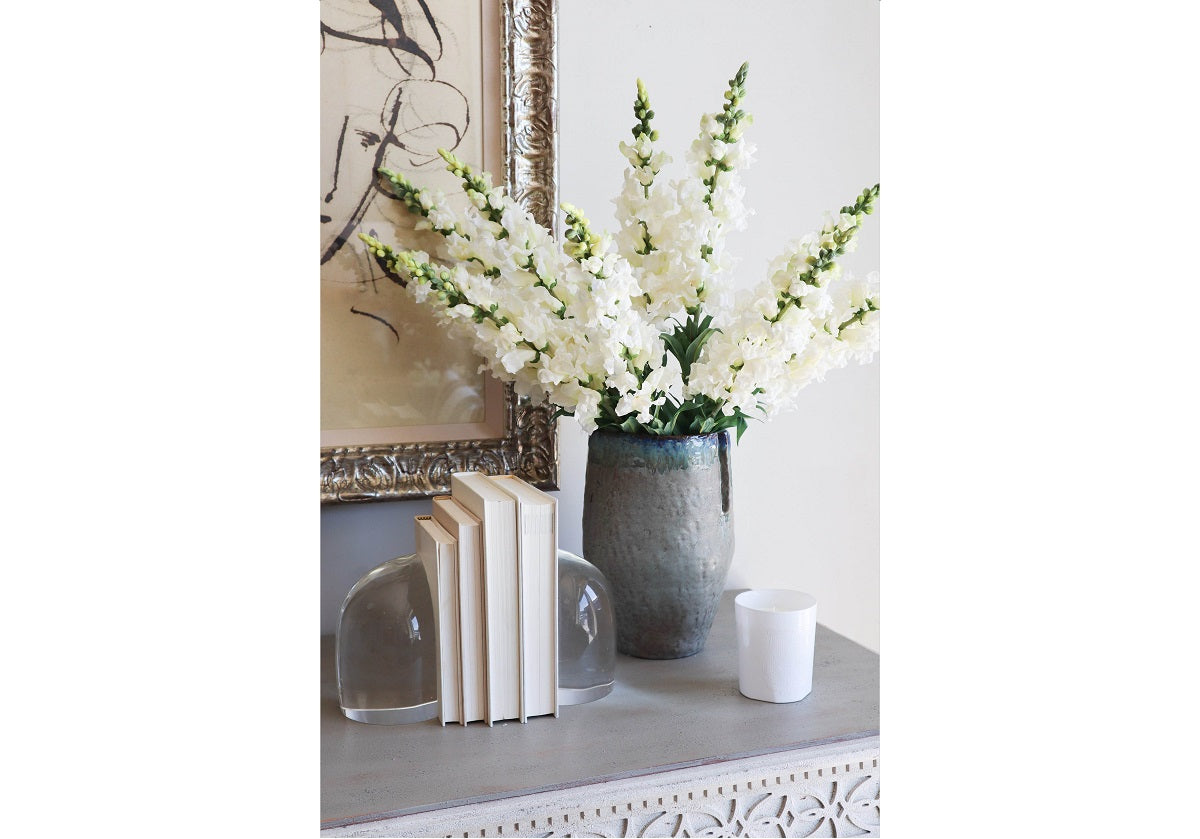 crystal bookends pictured ona dresser with books in between them and a vase filled with flowers. 