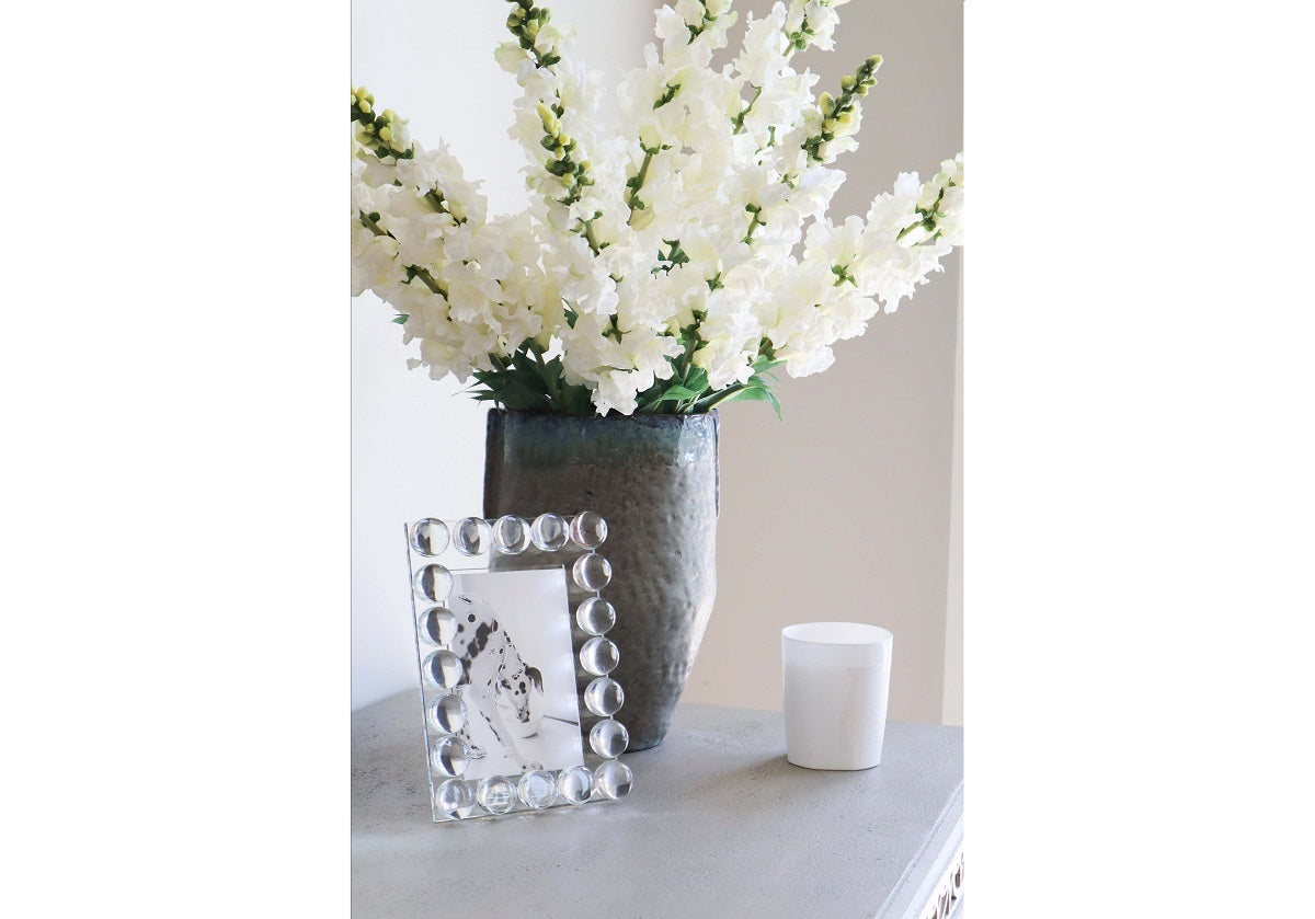 the crystal orb frame is on a table with a vase of flowers. 