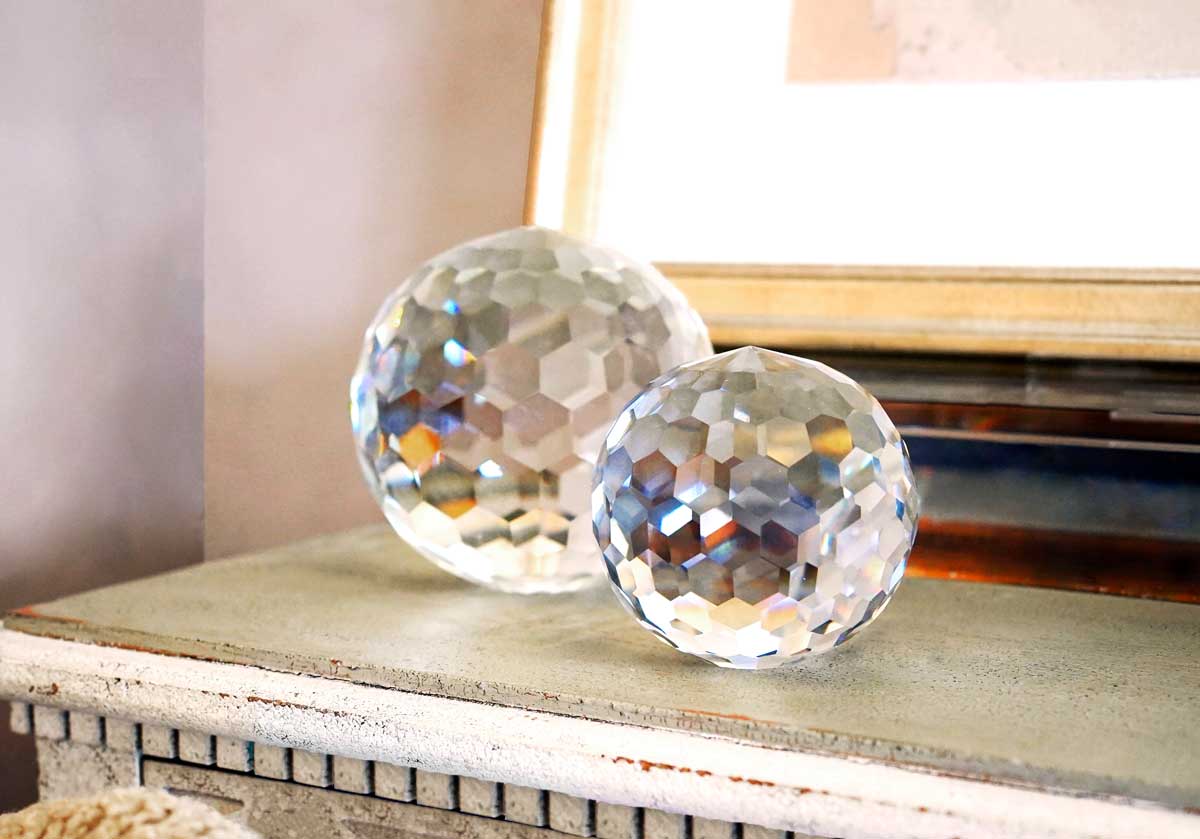 2 crystal orbs are next to each other on a dresser. 