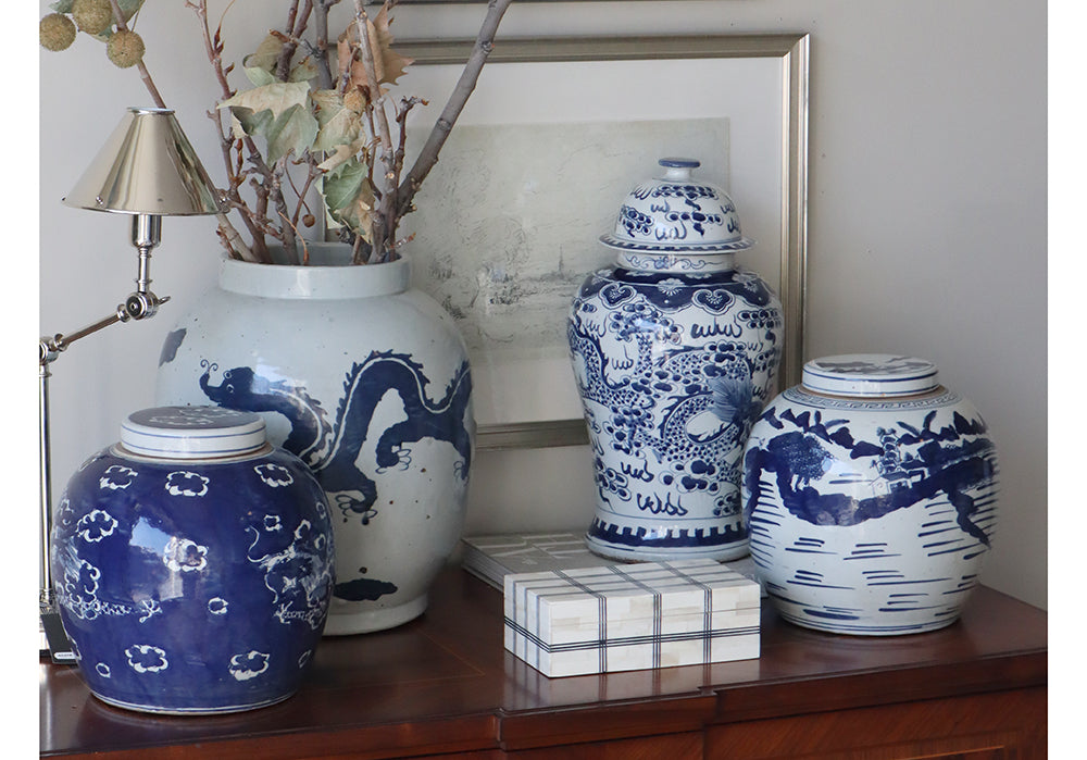 domino plaid box on a dark wood dresser with 4 blue and white vases.