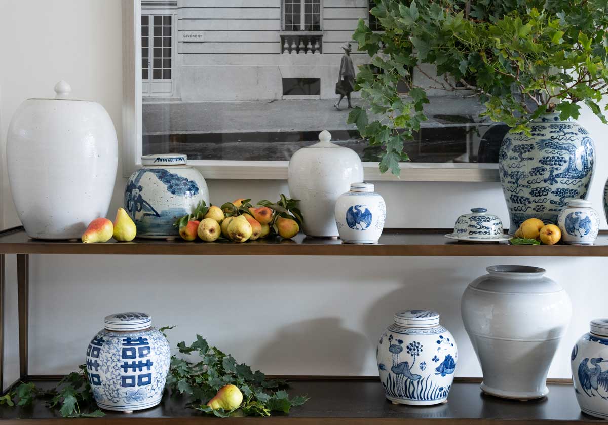 two wood shelves adorned in leaves and blue and white jars. the double happiness jar is in the bottom left corner by itself. 