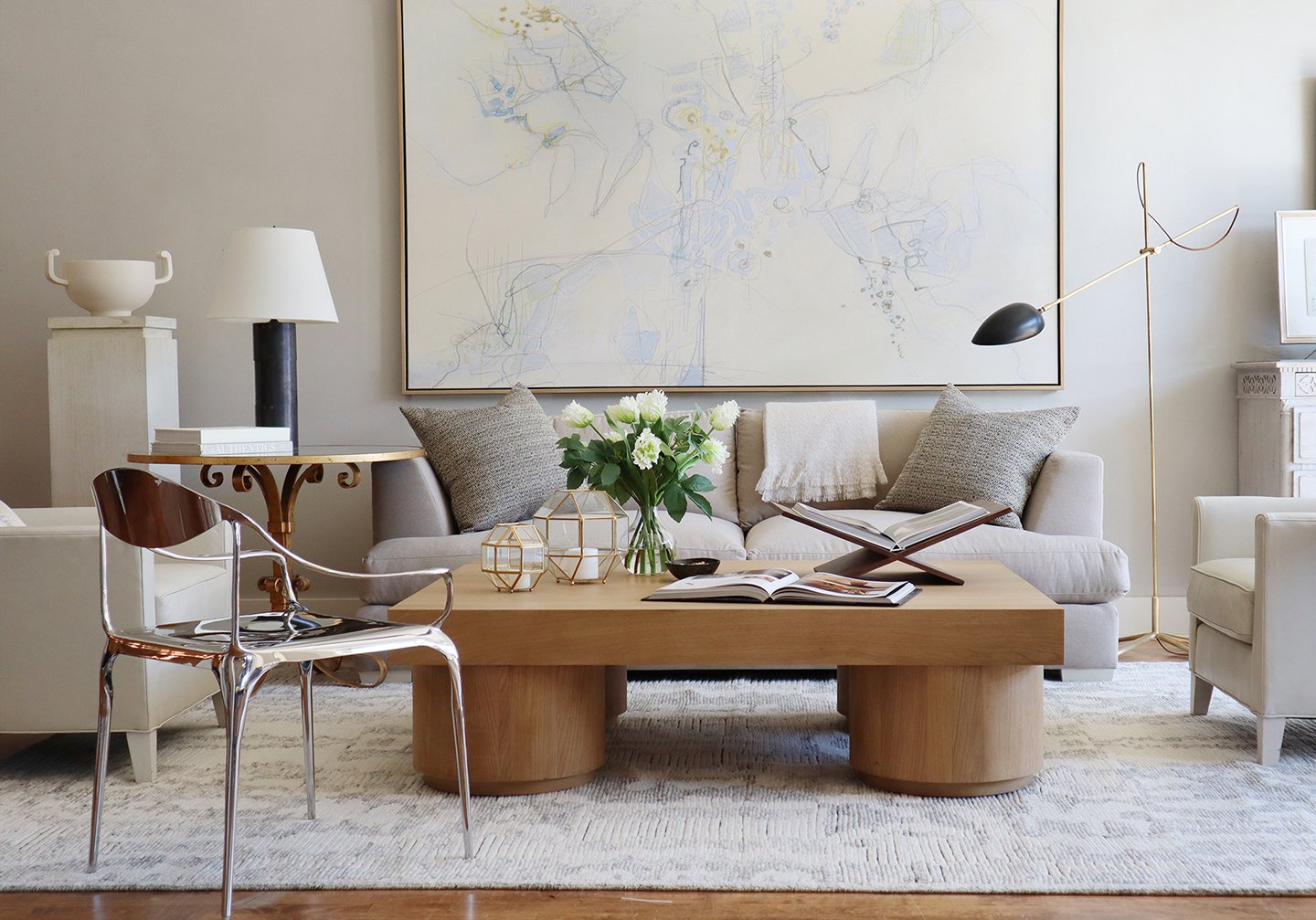 in the center of the living room there is a large duke cocktail table with a book display on it, a book, and decorative items. 