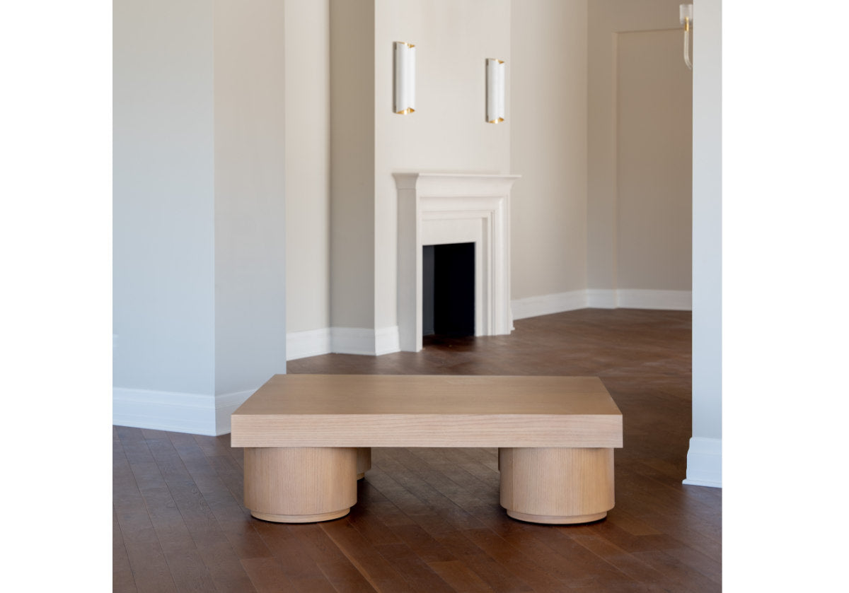 in an empty room with a fireplace, the duke cocktail table sits in the middle of a hallway. 