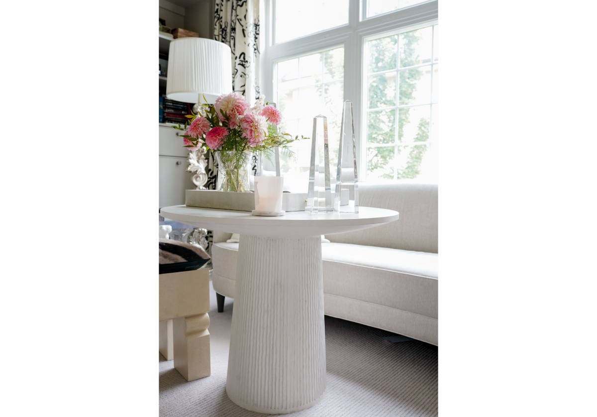 three large crystal obelisks can be seen on the lucca side table with a candle and a lamp, and some flowers in a vase. 