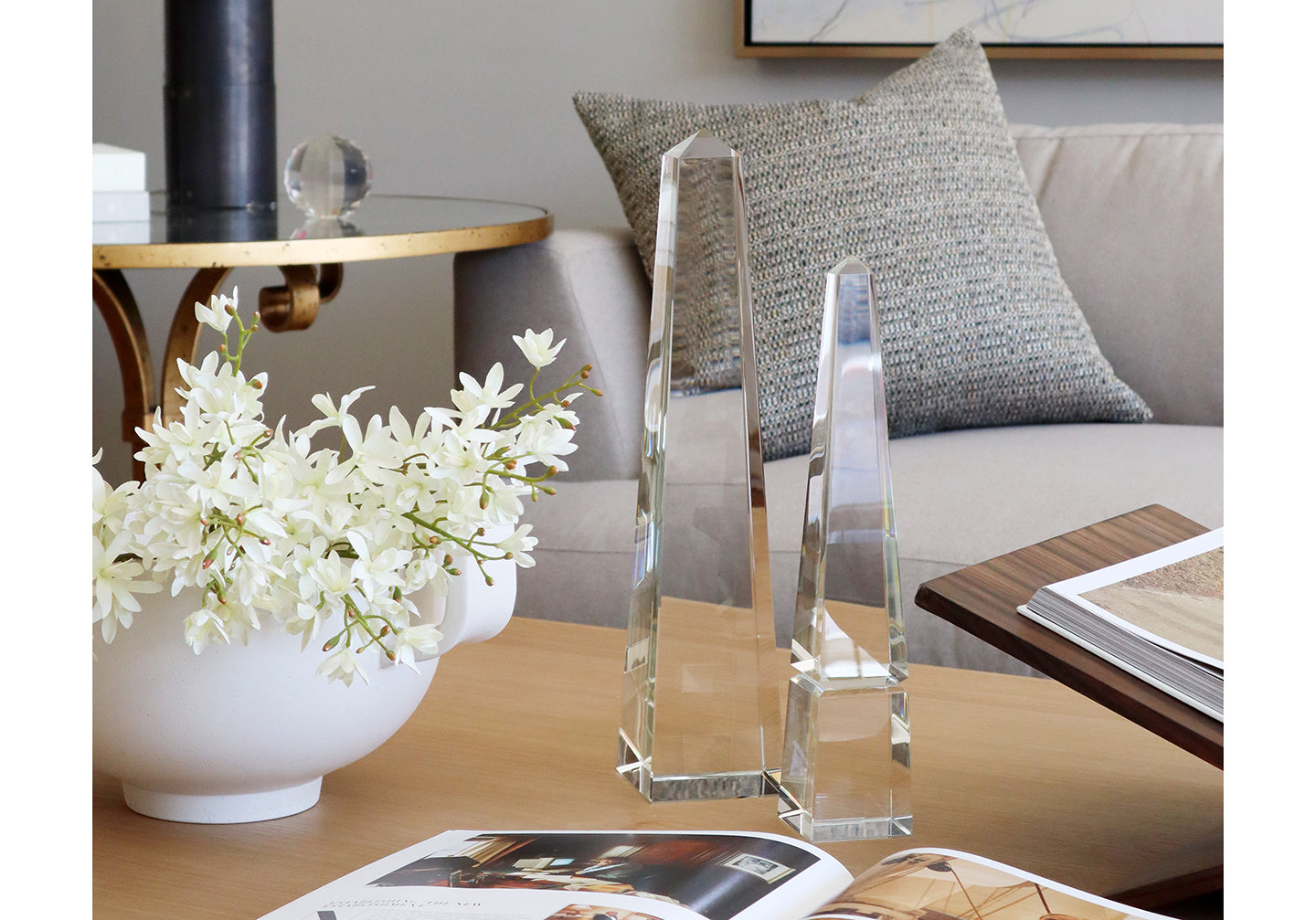 two different sized obelisks are seen on a table next to a bowl of flowers. 