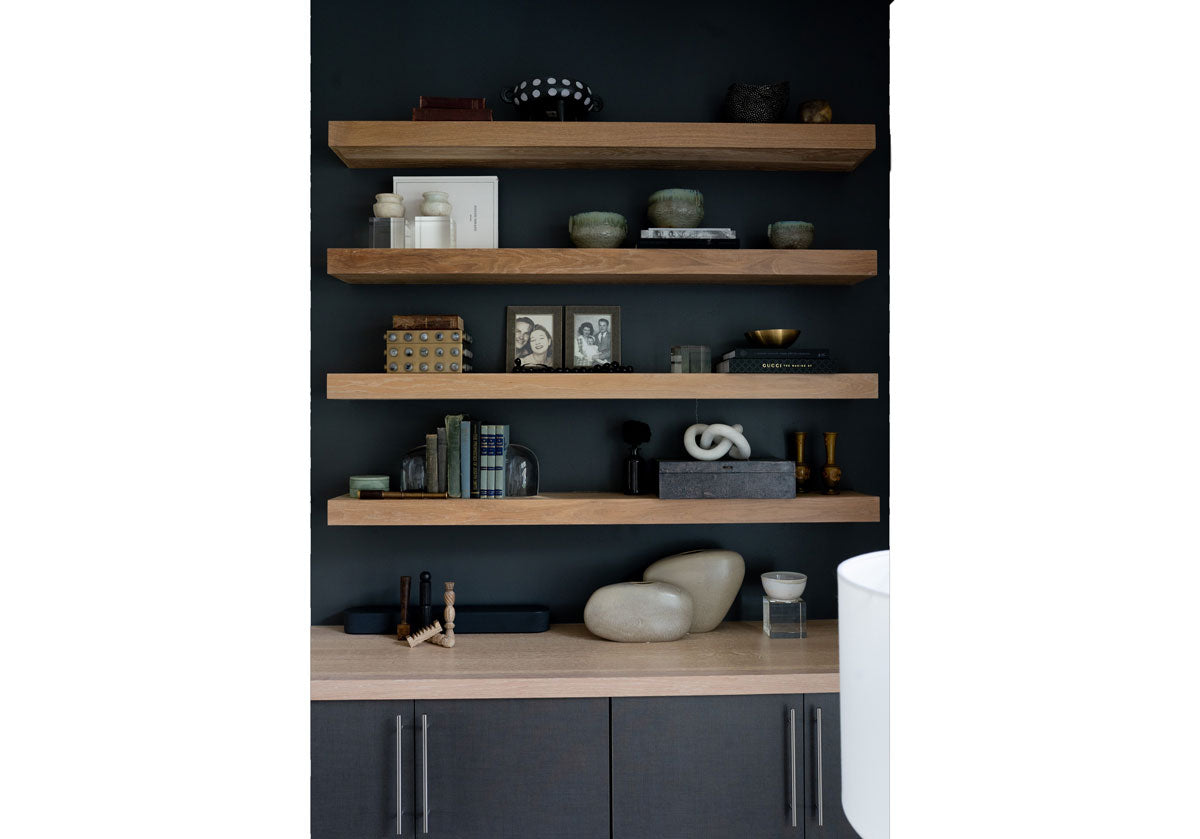 lifestyle picture of floating shelves above a cabinet with various some decor items. such as gold and wooden vase, crystal bookends and cubes and decorative boxes. 