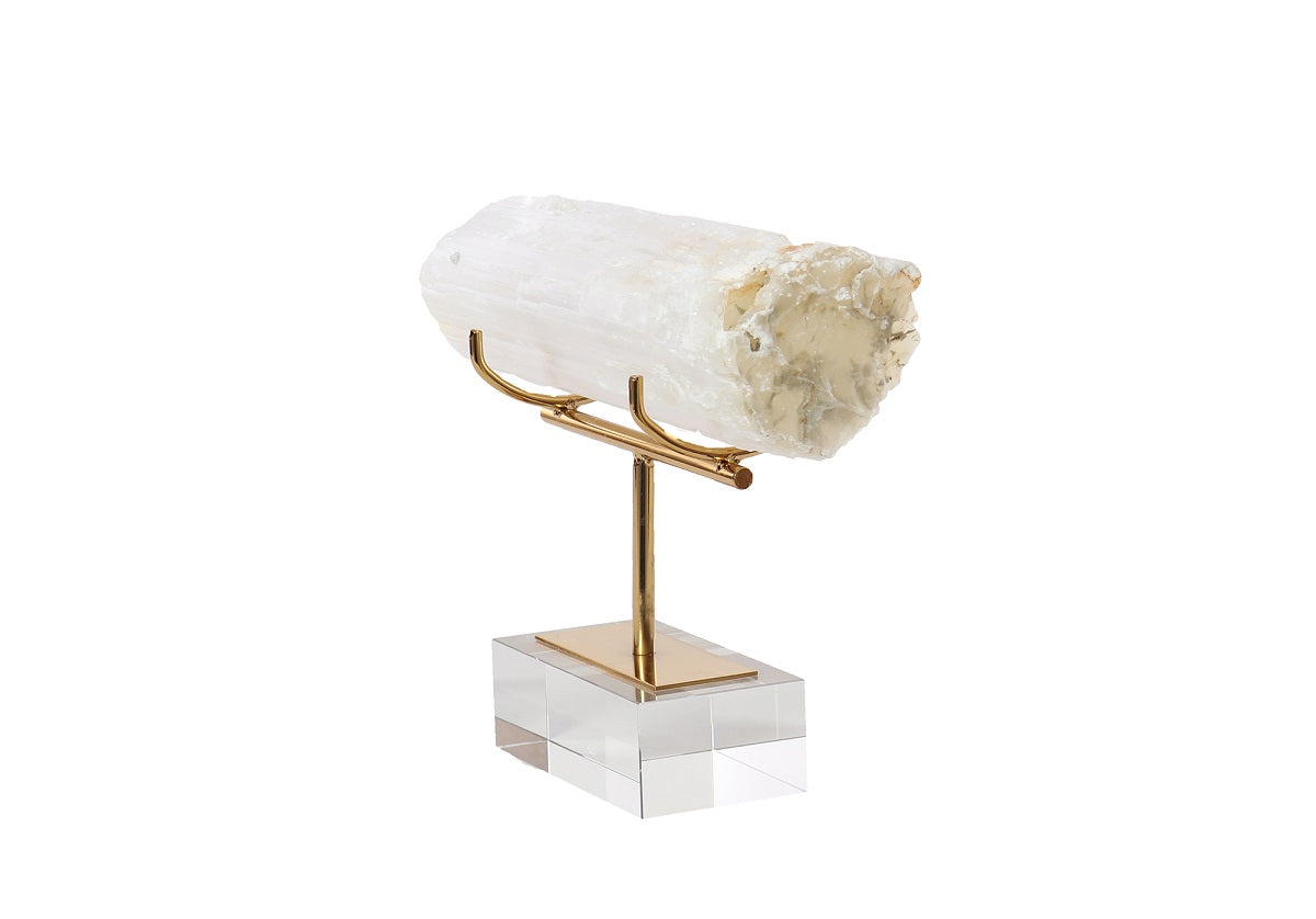 The Alice Lane Home Collection SELENITE CRYSTAL features a large, rough, white specimen with a natural shape, textured surface, and calming properties. It is elegantly mounted on a gold metal stand with a clear square base.