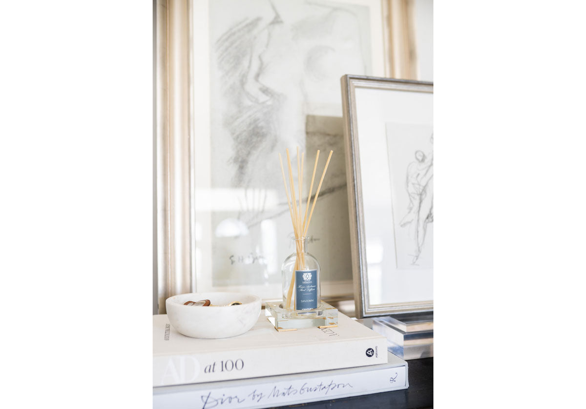 Photo of the crystal candle diffuser with scented sticks and a marble bowl on top of books. 